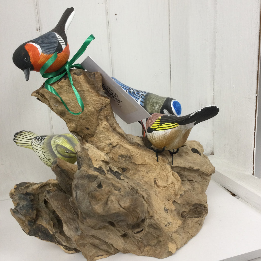 Vier geschilderde vogels op wortel. 